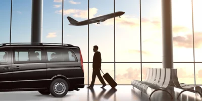Havalimanında lüks Mercedes minibüs ve valizini taşıyan bir yolcu; otelinize kolay ulaşım için ideal transfer hizmeti.