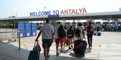 Antalya Havalimanı'ndan çıkan yolcular, valizleriyle birlikte transfer hizmeti için ilerliyor.
